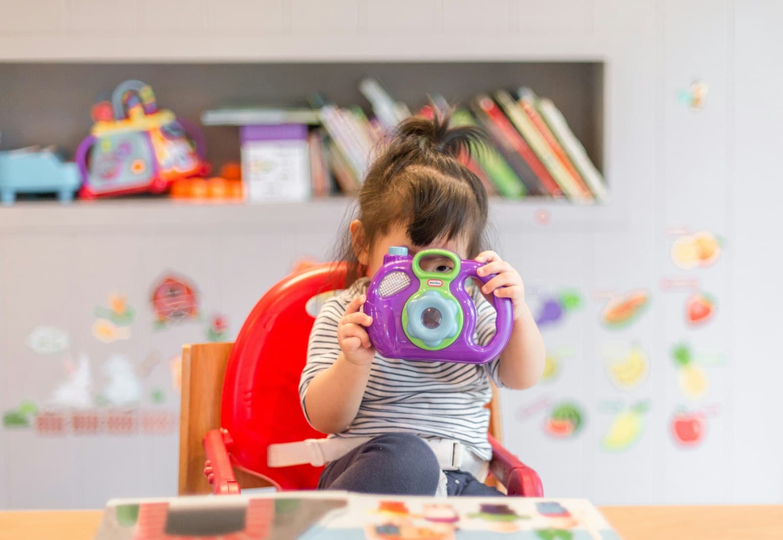 Niña pequeña mirando a través de una cámara de fotos de juguete